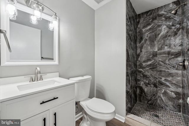 bathroom featuring vanity, a shower stall, toilet, and baseboards