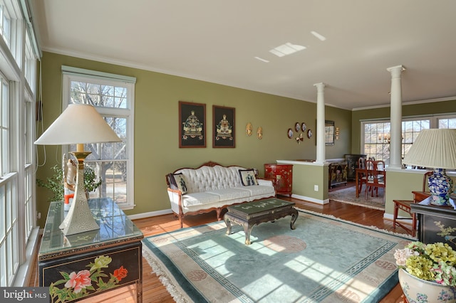 living area with crown molding, a healthy amount of sunlight, decorative columns, and wood finished floors