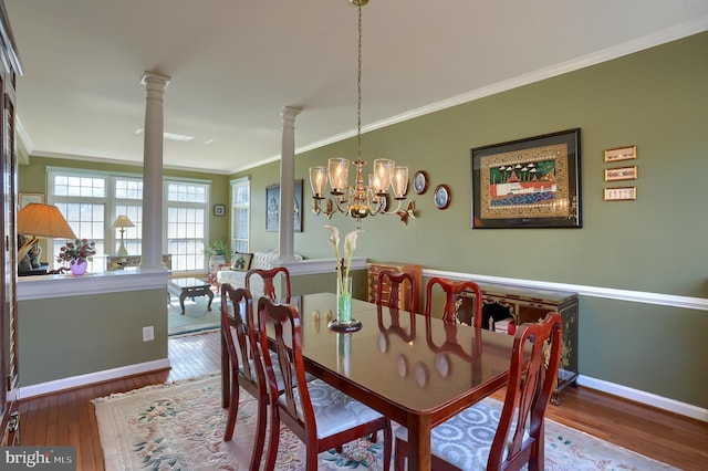 dining room featuring baseboards, wood-type flooring, decorative columns, and crown molding