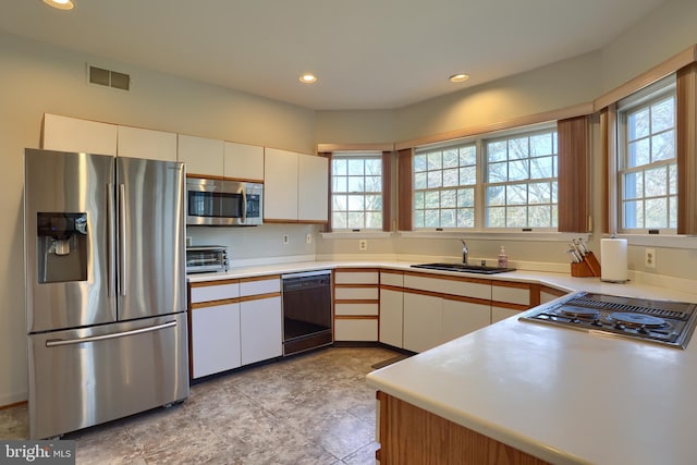 kitchen featuring black appliances, white cabinetry, visible vents, and a sink