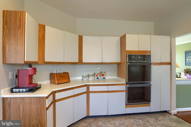 kitchen with dobule oven black, white cabinetry, and light countertops