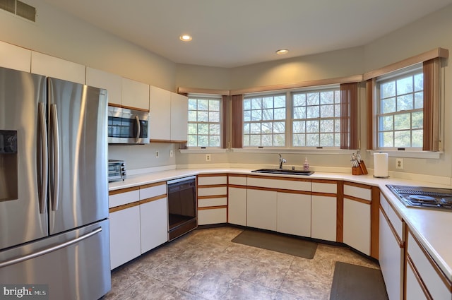 kitchen featuring white cabinets, visible vents, a sink, and black appliances