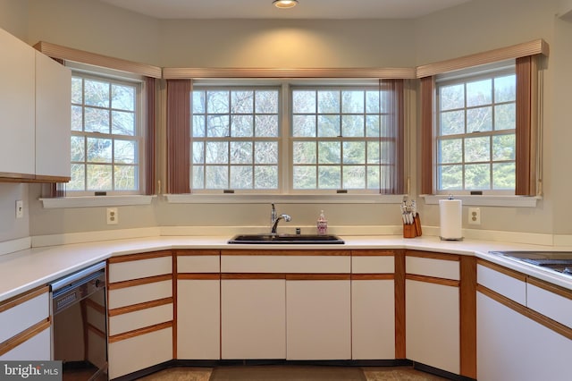 kitchen with light countertops, white cabinets, dishwasher, and a sink