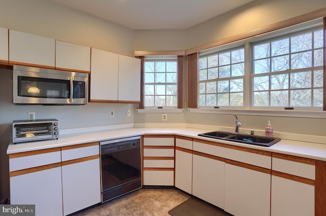 kitchen featuring a sink, stainless steel microwave, white cabinets, and dishwasher