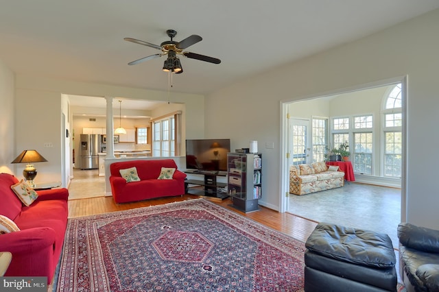 living room with ceiling fan, baseboards, and wood finished floors