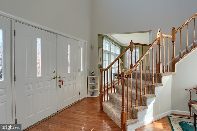 foyer featuring baseboards, hardwood / wood-style floors, and stairs