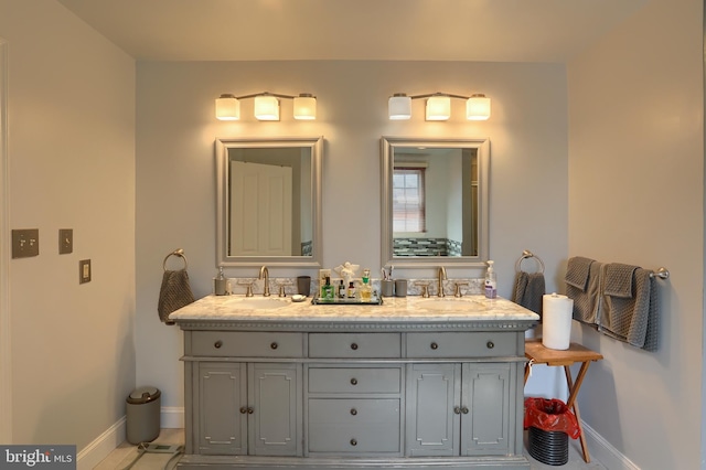 bathroom with double vanity, baseboards, and a sink