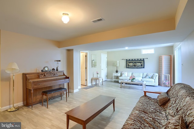 living room featuring light wood-type flooring, visible vents, and baseboards