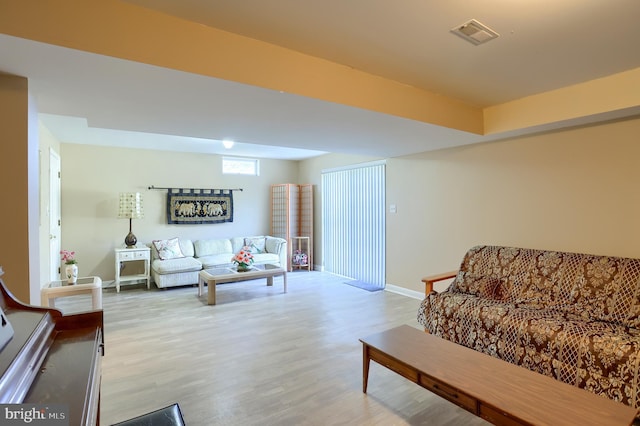 living room featuring visible vents, light wood-style flooring, and baseboards