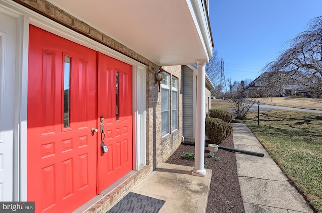 property entrance with covered porch and a yard