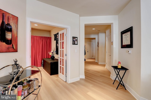 corridor with light wood-type flooring and baseboards