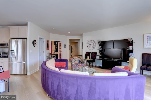 living area with light wood-style floors, a toaster, and baseboards