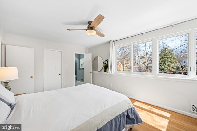 bedroom featuring visible vents, multiple windows, baseboards, and wood finished floors