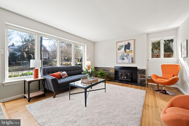 living room with a healthy amount of sunlight, a lit fireplace, and hardwood / wood-style flooring