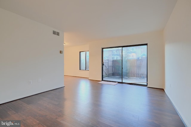 spare room with baseboards, visible vents, and dark wood finished floors