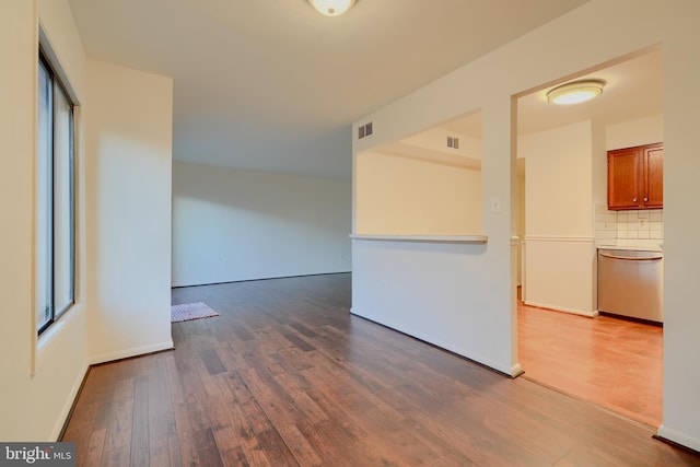 spare room with wood finished floors, visible vents, and baseboards