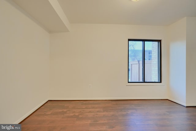 spare room with dark wood-type flooring and baseboards