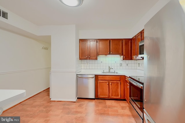 kitchen featuring stainless steel appliances, a sink, light countertops, decorative backsplash, and brown cabinets