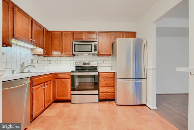 kitchen featuring light countertops, appliances with stainless steel finishes, backsplash, and brown cabinets