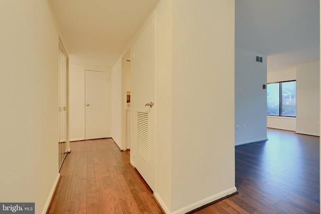 corridor featuring visible vents, baseboards, and wood finished floors