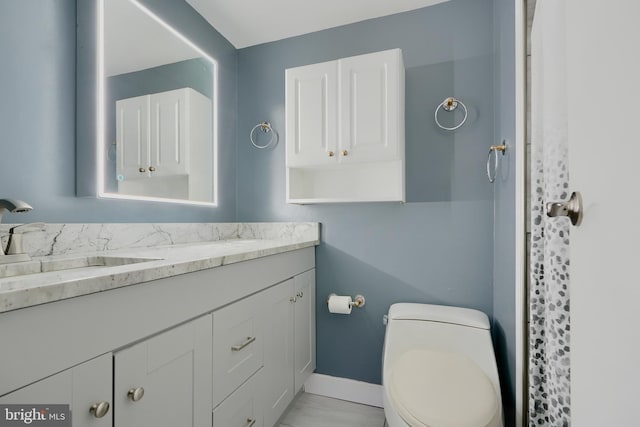 bathroom featuring toilet, baseboards, and vanity