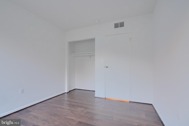 unfurnished bedroom with baseboards, a closet, visible vents, and wood finished floors