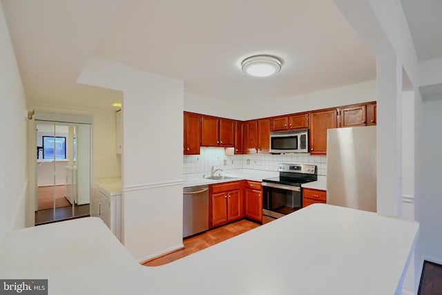 kitchen featuring backsplash, stainless steel appliances, light countertops, and independent washer and dryer