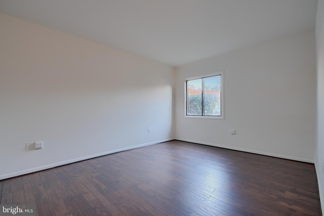 empty room featuring dark wood-type flooring and baseboards