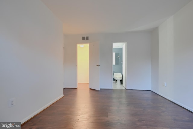 empty room featuring dark wood-style floors, baseboards, and visible vents