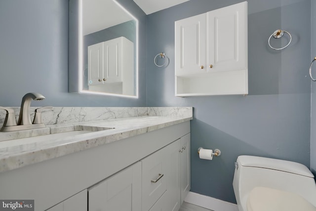 bathroom featuring baseboards, vanity, and toilet