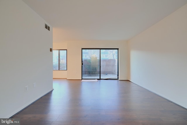 spare room with a wealth of natural light, dark wood-style flooring, and visible vents