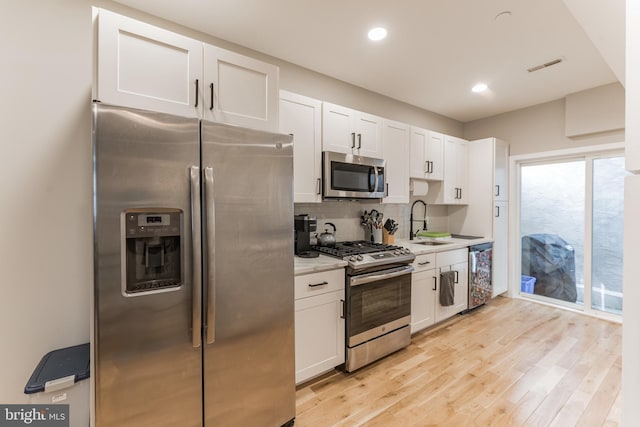 kitchen featuring visible vents, stainless steel appliances, light countertops, white cabinetry, and a sink