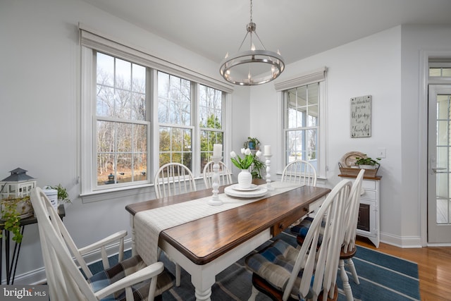 dining space with an inviting chandelier, baseboards, and wood finished floors