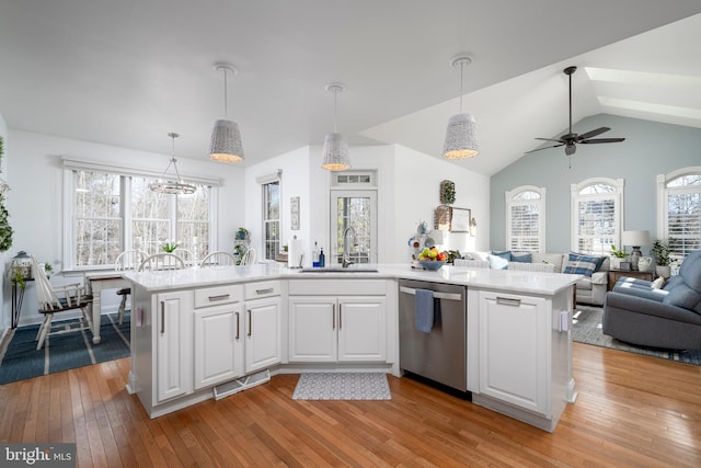 kitchen with light countertops, stainless steel dishwasher, open floor plan, white cabinets, and a sink