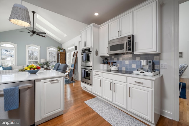 kitchen with stainless steel appliances, lofted ceiling, light countertops, light wood-style floors, and open floor plan