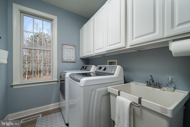 washroom with cabinet space, visible vents, a sink, independent washer and dryer, and baseboards