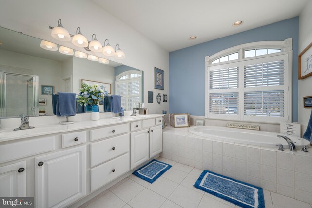 bathroom with double vanity, a stall shower, a sink, tile patterned flooring, and a bath