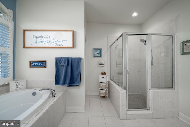 bathroom with a stall shower, tile patterned flooring, a garden tub, and baseboards