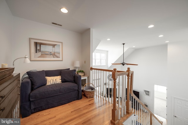 living area featuring recessed lighting, visible vents, light wood-style flooring, and an upstairs landing