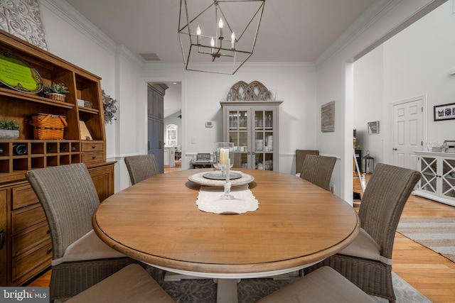 dining room with crown molding, visible vents, a notable chandelier, and wood finished floors