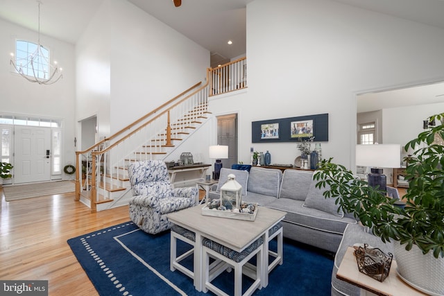 living area featuring an inviting chandelier, stairs, a high ceiling, and wood finished floors