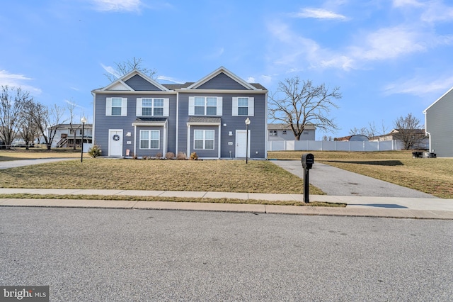 view of front of property featuring a front yard, fence, and driveway