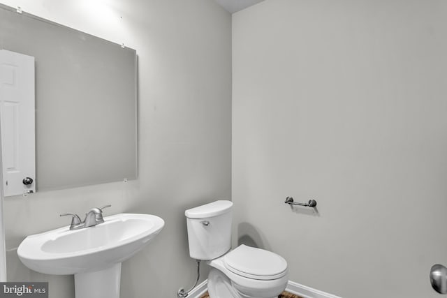 bathroom featuring a sink, baseboards, and toilet