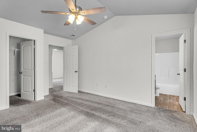 unfurnished bedroom featuring carpet, visible vents, lofted ceiling, a closet, and connected bathroom