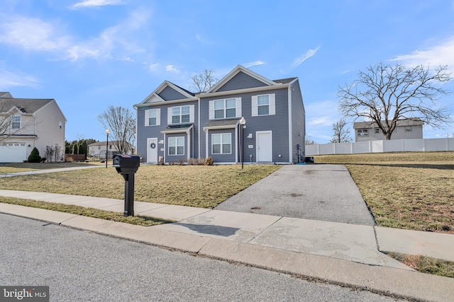 view of front of property with driveway, a front lawn, and fence