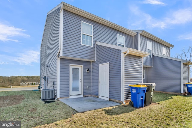 rear view of property featuring central air condition unit, a lawn, and a patio