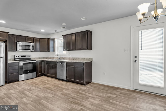 kitchen featuring a notable chandelier, stainless steel appliances, light wood-style floors, dark brown cabinetry, and light countertops