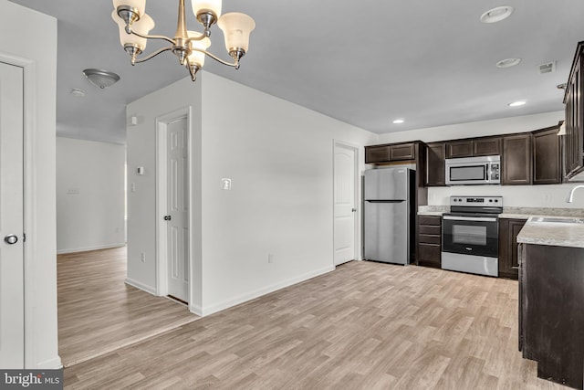 kitchen featuring light wood finished floors, dark brown cabinets, a chandelier, light countertops, and appliances with stainless steel finishes