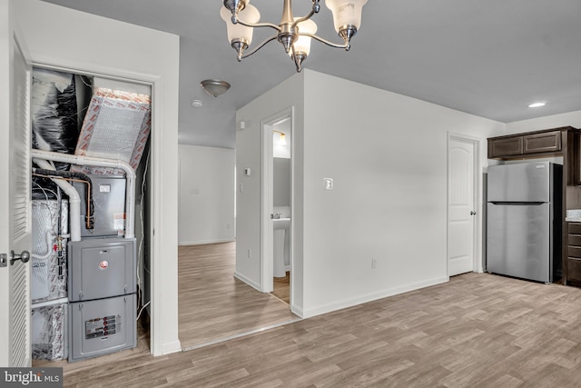 interior space featuring light wood-type flooring, dark brown cabinetry, a chandelier, and freestanding refrigerator