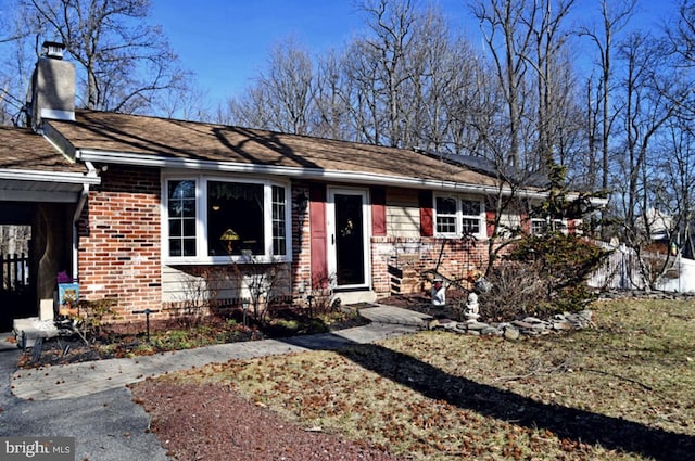 ranch-style house with a chimney and brick siding